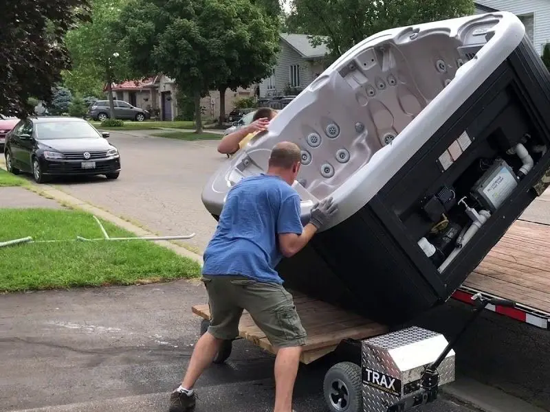 A hot tub tipped on its side and rolled onto a flatbed trailer